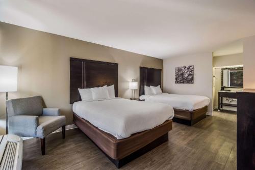 una habitación de hotel con 2 camas y una silla en Clarion Inn & Suites en Florence