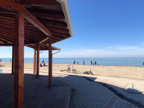 a beach with a wooden pavilion and people on the beach at Gazi’s Apartament for Rent in Golem