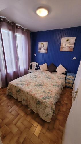 ein Schlafzimmer mit einem großen Bett in einer blauen Wand in der Unterkunft Hollywood E24 - T2 avec terrasse à 2 minutes de la plage in Valras-Plage