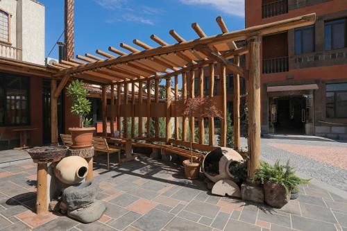 a wooden pergola with potted plants on a patio at H Resort Hotel Vagharshapat Armenia in Vagharshapat