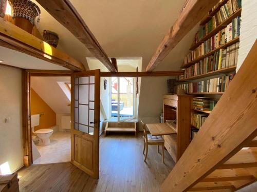 Una habitación abuhardillada con una escalera y una estantería. en Haus Störtebeker, en Wismar