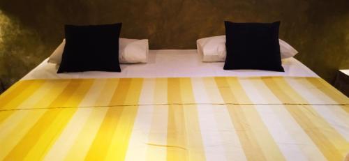 a bed with black and yellow sheets and pillows at Negombo The Nature Villa and Cabanas in Negombo