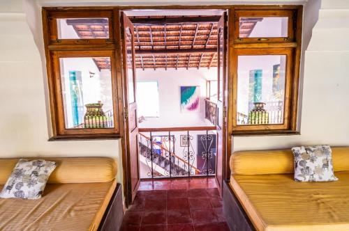 two beds in a room with two windows at Island House Goa in Divar