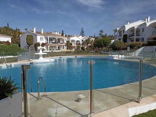 una gran piscina azul con casas en el fondo en Le joyau Andalou, en Estepona