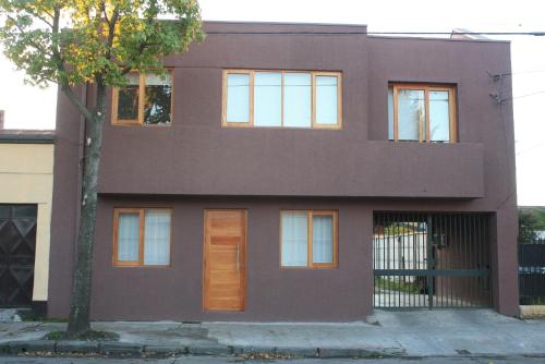 a brown house with a tree in front of it at Hostal Buró in Concepción
