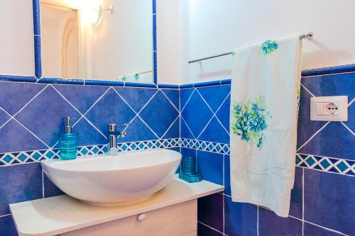 a blue tiled bathroom with a sink and a mirror at Casa Cinque in Praiano