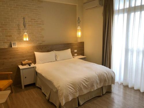 a bedroom with a white bed and a brick wall at Daybreak in Taitung City