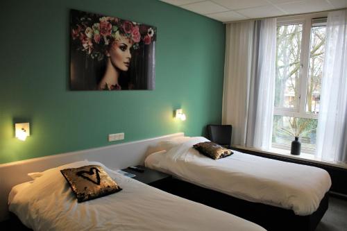 twee bedden in een kamer met een schilderij aan de muur bij Hotel Restaurant de Jonge Heertjes in Aalsmeer