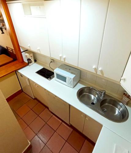a small kitchen with a sink and a microwave at Plaza Andalucía Edificio Enebro 4-6 pax in Sierra Nevada