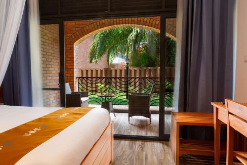 a bedroom with a bed and a balcony with a patio at Hotel Chez Lando in Kigali