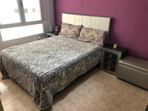 1 dormitorio con cama y pared púrpura en Aléjate de todo pero quédate cerca, en Oviedo