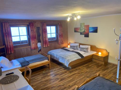 a bedroom with two beds and a table and windows at Reiterhof Familie Laubichler in Schladming