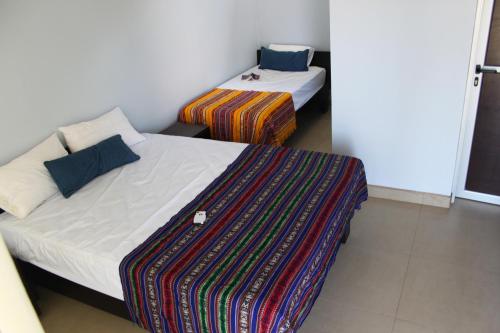 a bedroom with two beds and a colorful blanket at Room2Board Hostel and Surf School in Jacó