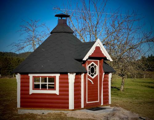 uma pequena casa vermelha com um telhado preto em Villa 200m2 avec PISCINE chauffée & SPA & sauna & kota-grill em Laval-sur-Vologne