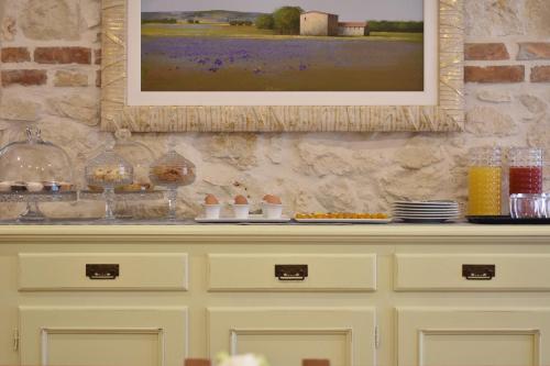 a painting hanging on a wall above a cabinet with food at Tenuta Micoli in Frisa