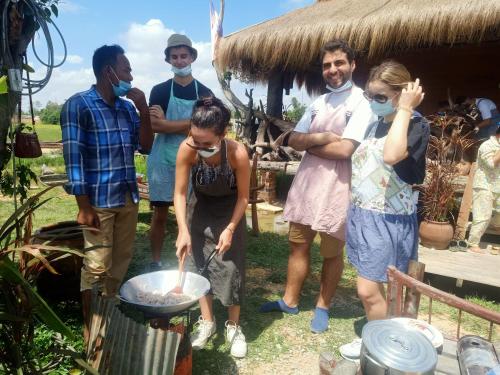 a group of people cooking food in a pan at Kakrona Pouk Homestay in Siem Reap