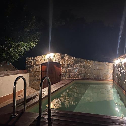 a swimming pool at night with a stone wall at SG Apartmán se soukromým wellness in Nová Paka
