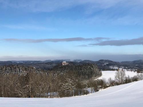 a snow covered hill with a house in the distance at SG Apartmán se soukromým wellness in Nová Paka