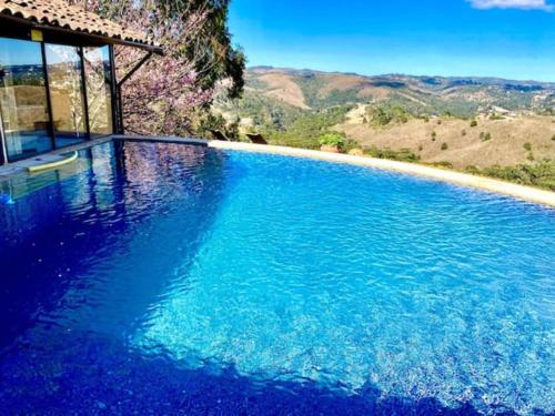 uma grande piscina azul com vista para as montanhas em Chalé Vista Privilegiada em Campos do Jordão