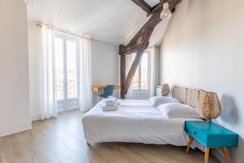 - une chambre avec un lit blanc et une table bleue dans l'établissement Le Panorama, à Clermont-Ferrand