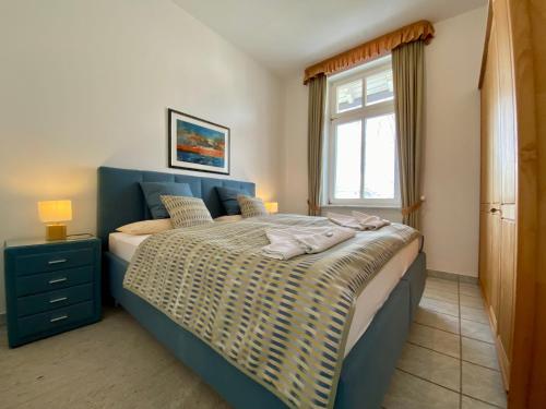 Schlafzimmer mit einem Bett mit blauem Kopfteil und einem Fenster in der Unterkunft Villa Caprivi - 6 in Heringsdorf