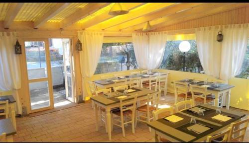 a restaurant with tables and chairs in a room at Hotel Enrica in Cervia