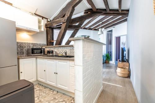 une cuisine avec des placards blancs et un mur en briques dans l'établissement Le Panorama, à Clermont-Ferrand