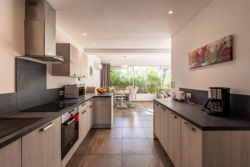 une cuisine avec des armoires blanches et des comptoirs noirs dans l'établissement Les Arcades de Cala Rossa, à Lecci