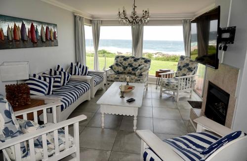 a living room with chairs and a table and a fireplace at Whales & Waves in Hermanus