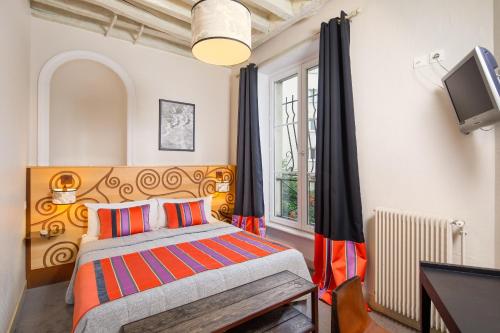 a bedroom with a bed and a tv and a window at Hôtel Claret Bercy in Paris