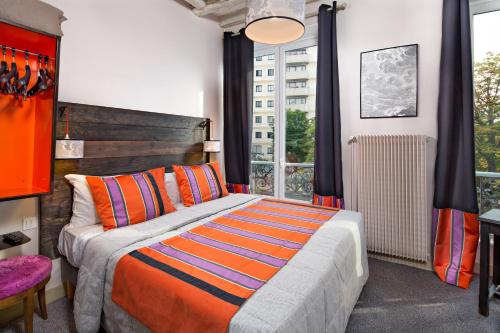 a bedroom with a bed and a large window at Hôtel Claret Bercy in Paris