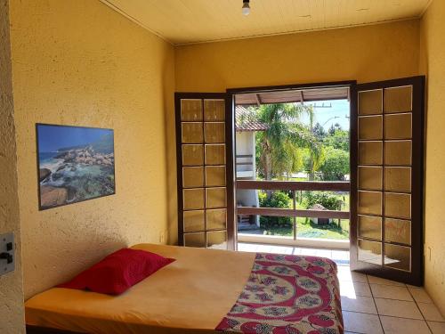 a bedroom with a bed and a large window at Residencial Villa Luana in Garopaba