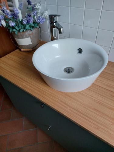 a white sink on top of a wooden counter with flowers at Casa Vacanza Nonno Gigi in Mandello del Lario