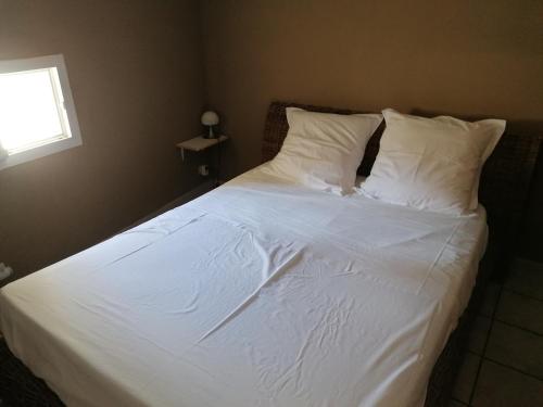 Una cama con sábanas blancas y almohadas en un dormitorio en Maison entière, en Saint-Paul-les-Fonts