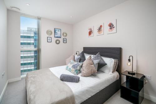 um quarto com uma cama com almofadas e uma janela em Croydon Saffron Mordern Apartment em Croydon