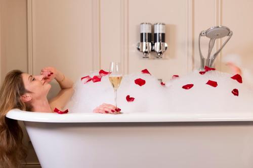 a woman laying in a bath tub with a glass of wine at Ermitage - Mont-Saint-Michel in Beauvoir
