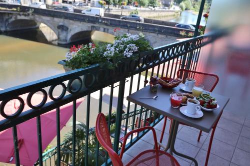 a table and chairs on a balcony with a view of a bridge at Best Western Le Pont d'Or in Figeac