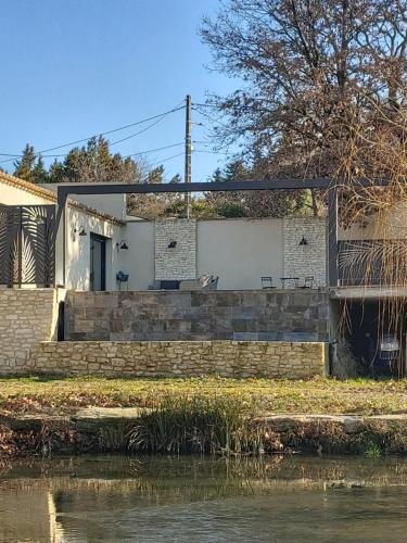 a house next to a body of water at Un petit coin de Bali avec SPA et piscine privés in Carpentras