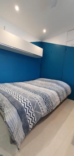 una cama en una habitación con una pared azul en Studio Apartment between Nice and Cannes - Marina baie des Anges - Beach, restaurants, shops - tea/coffee/sugar/bed linen and towels, en Villeneuve-Loubet