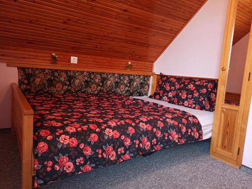1 dormitorio con 1 cama con edredón de flores en Nárcisz Vendégház en Mezőkövesd