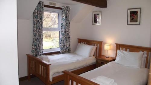 two beds in a room with a window at Craobh Marina Cottages in Craobh Haven