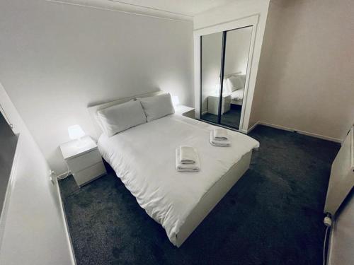 sypialnia z białym łóżkiem i lustrem w obiekcie Modern 2 Bedroom Apartment With Free Parking w Glasgow