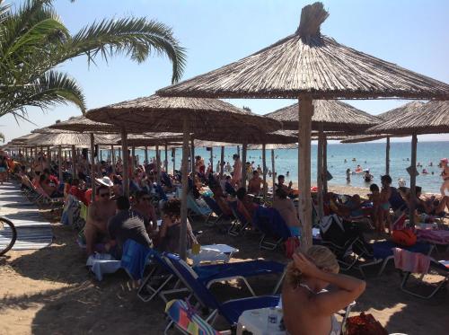 a crowd of people sitting in chairs under umbrellas on a beach at Hotel Nautilos in Sozopoli