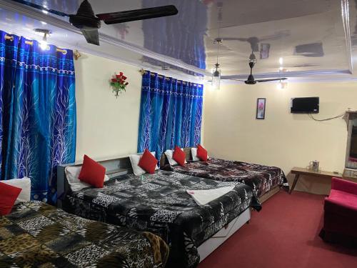 a bedroom with two beds and blue curtains at Hotel Young Mamta in Srinagar