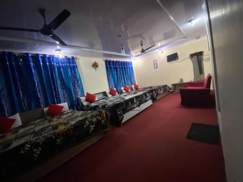 a room with couches and red chairs and blue curtains at Hotel Young Mamta in Srinagar