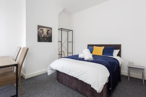 1 dormitorio con 1 cama con almohadas azules y amarillas en Clayton House - Spacious home near Etihad Stadium en Mánchester