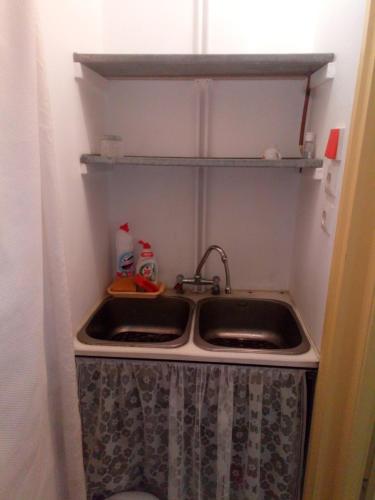 a kitchen sink in a small kitchen with a shelf at Agria Retur Vendégház in Eger