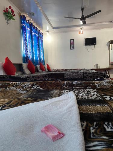 a room with several beds with blue curtains and red pillows at Hotel Young Mamta in Srinagar