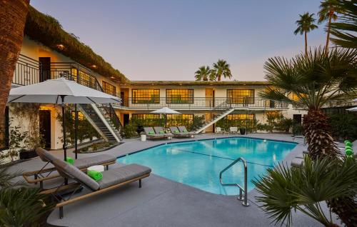 a swimming pool with lounge chairs and a building at Descanso Resort, A Men's Resort in Palm Springs