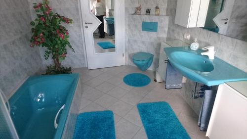 La salle de bains est pourvue d'un lavabo bleu, d'une baignoire et de toilettes. dans l'établissement Ferienwohnung Lang, à Nittenau